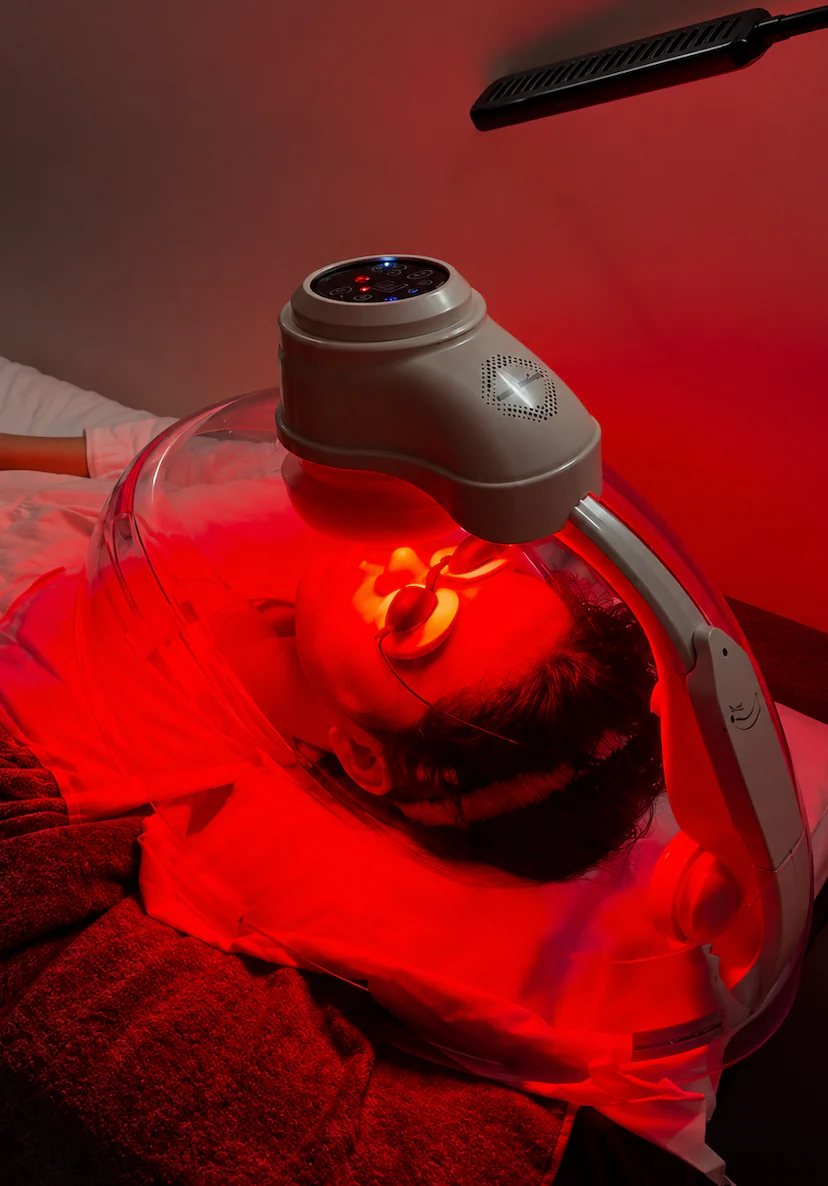 A client under the Astrodome canopy, red LED light filling the chamber