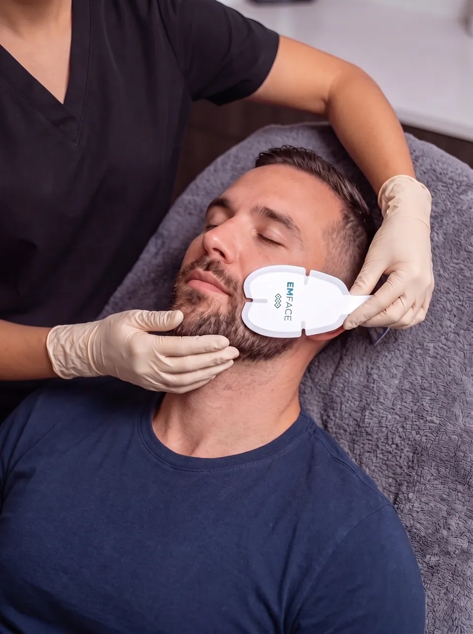 A clinician placing an EMFACE applicator on a patient's cheek