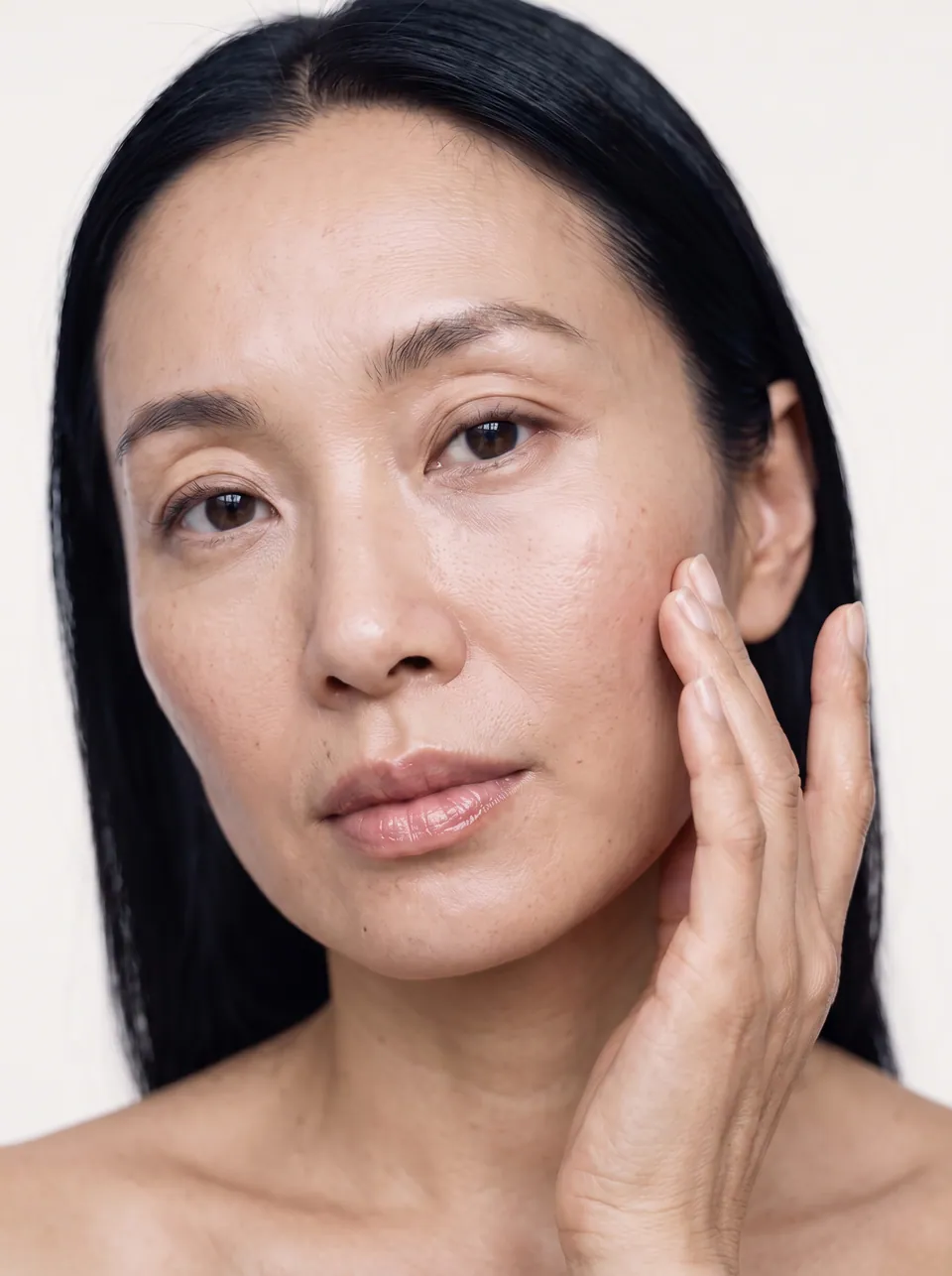 Close portrait of a woman with smooth, natural-looking skin, hand resting on her cheek