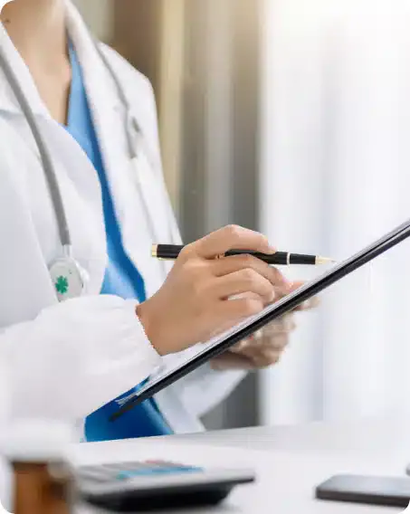 A doctor in a white coat making notes on a clipboard during a consultation