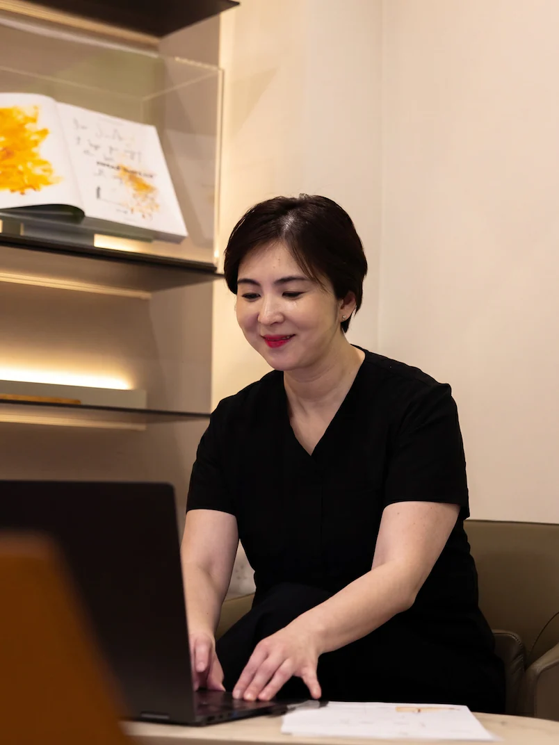 Dr Jinah Yoo working at a laptop in the clinic lounge