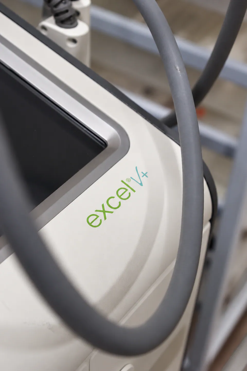 The excel V+ wordmark on the laser console beside its screen and delivery arm