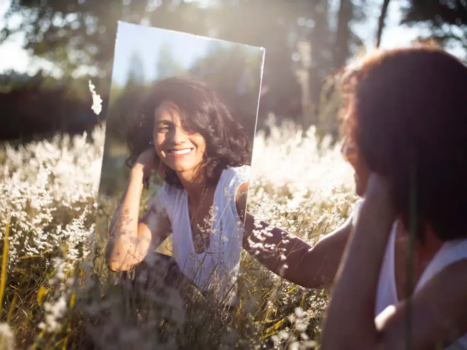 woman smiling, looking at herself in the mirror