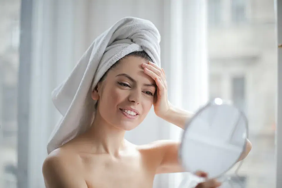 woman unlocking the secrets to clear, radiant skin and looking at her skin in a mirror
