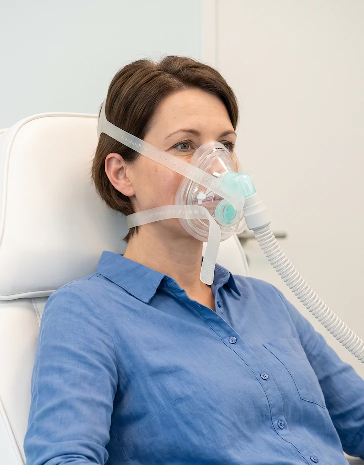 A patient seated in a treatment chair wearing the CellAir face mask