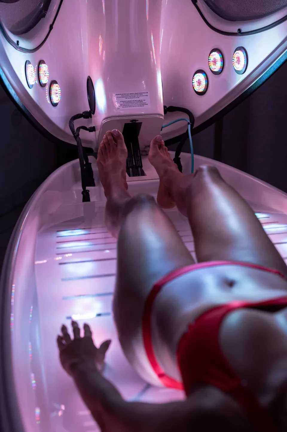 A person relaxing inside the Cocoon Wellness Pod under red light