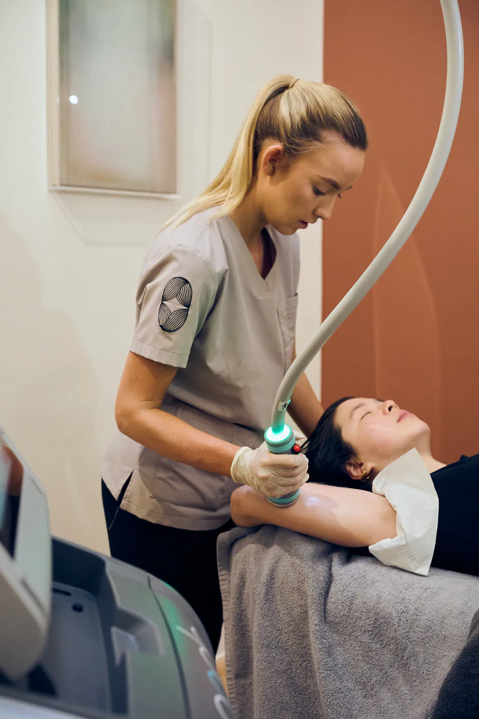 A practitioner treating a patient's upper arm with the Onda handpiece in the treatment room