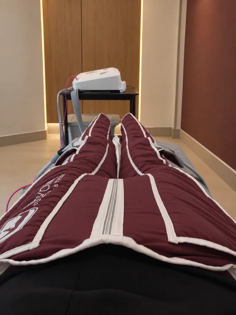 The Slimyonik suit inflated around a client's legs, the compression unit on a stand behind