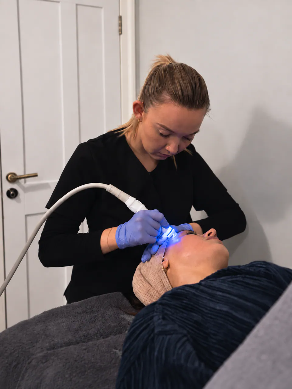 A therapist guiding the Aquapure handpiece across a client's face in the treatment room