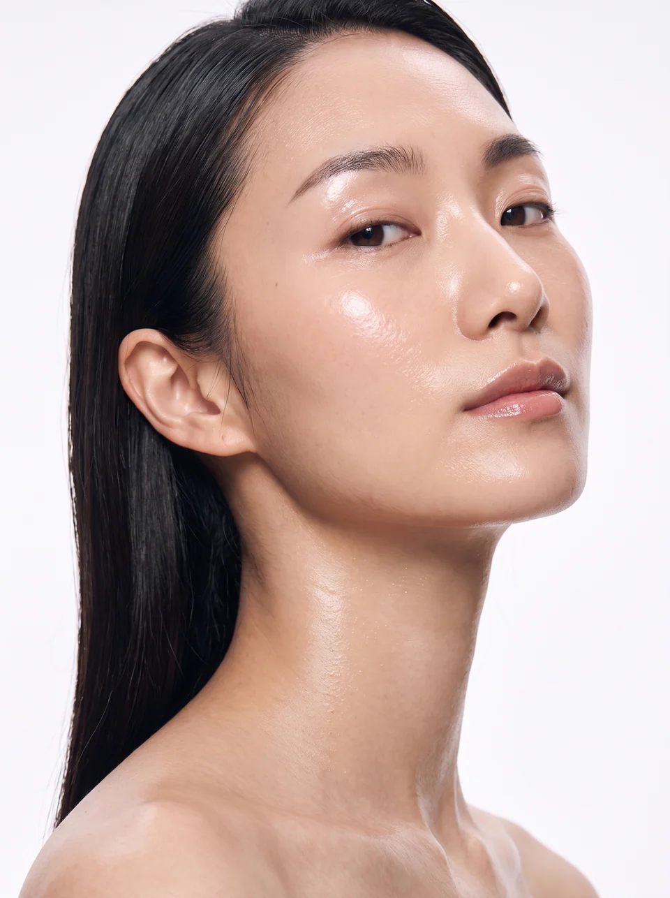 A woman with dewy, luminous skin, her hair swept back