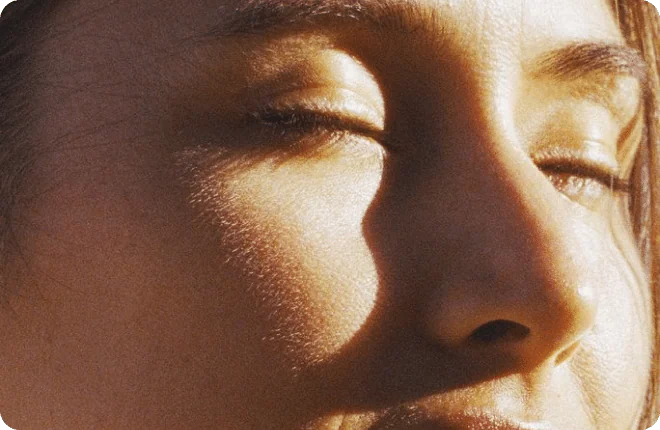 A woman with her eyes closed, face turned towards the sun