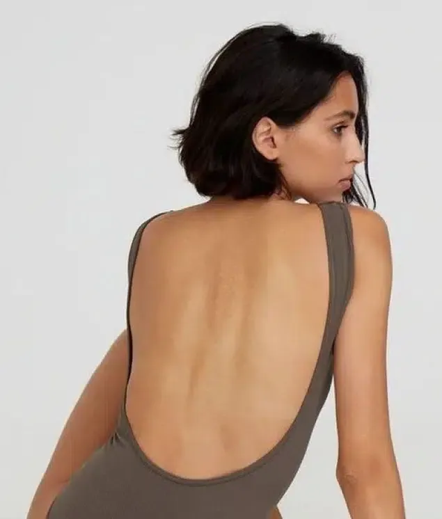 A woman in a low-back bodysuit, seen from behind