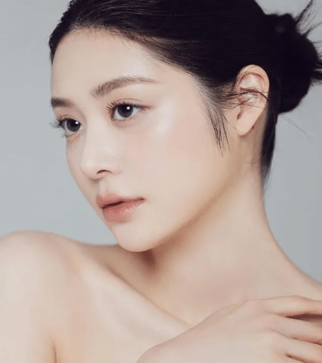 A woman with smooth, even skin, resting her head on her shoulder