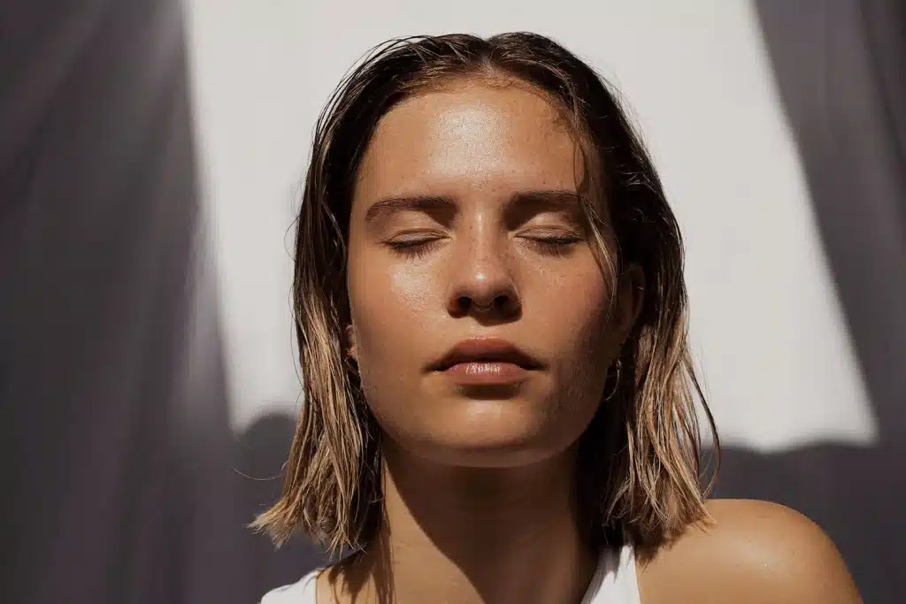Woman showing her skin in the sunlight with her eyes closed